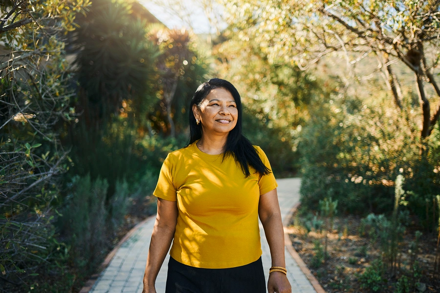 Woman walking on a sunny garden path.