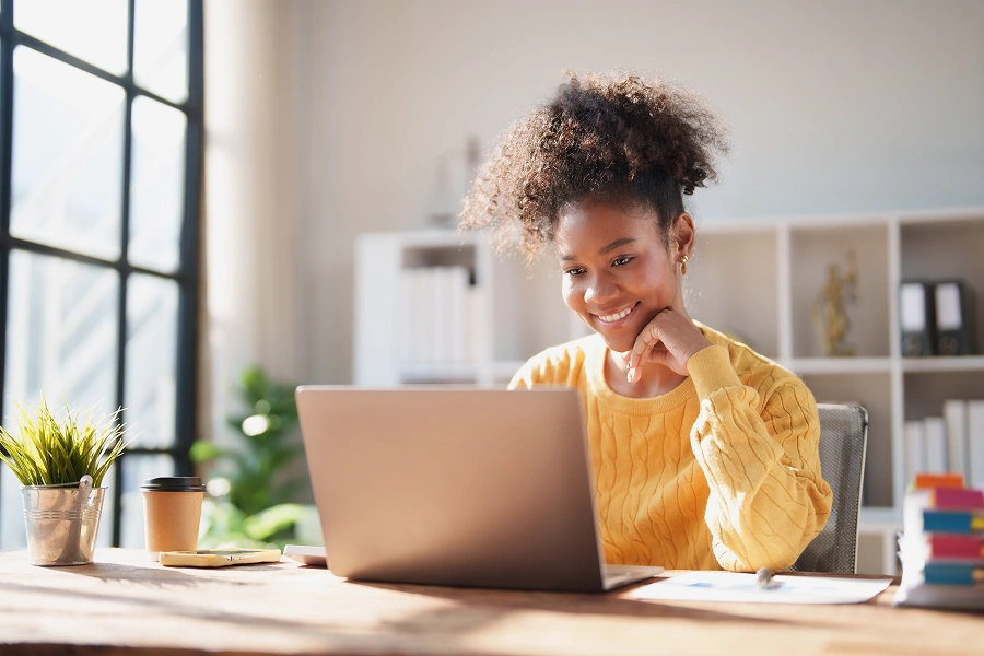 Smiling woman working on laptop at desk.