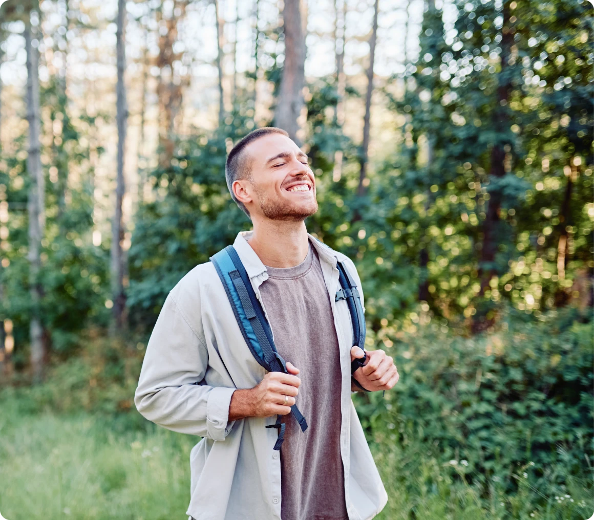 Man smiling while hiking in forest.