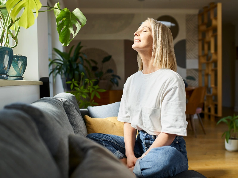 Woman enjoying sunlight in cozy living room.
