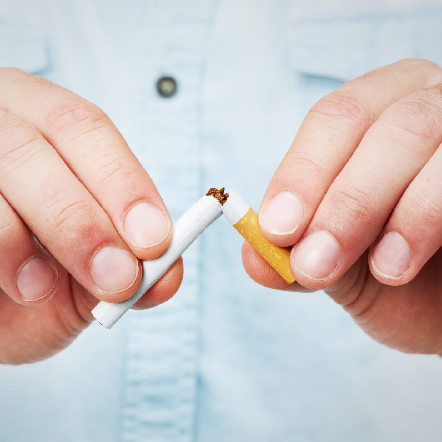 Closeup of a man breaking a cigarette in half